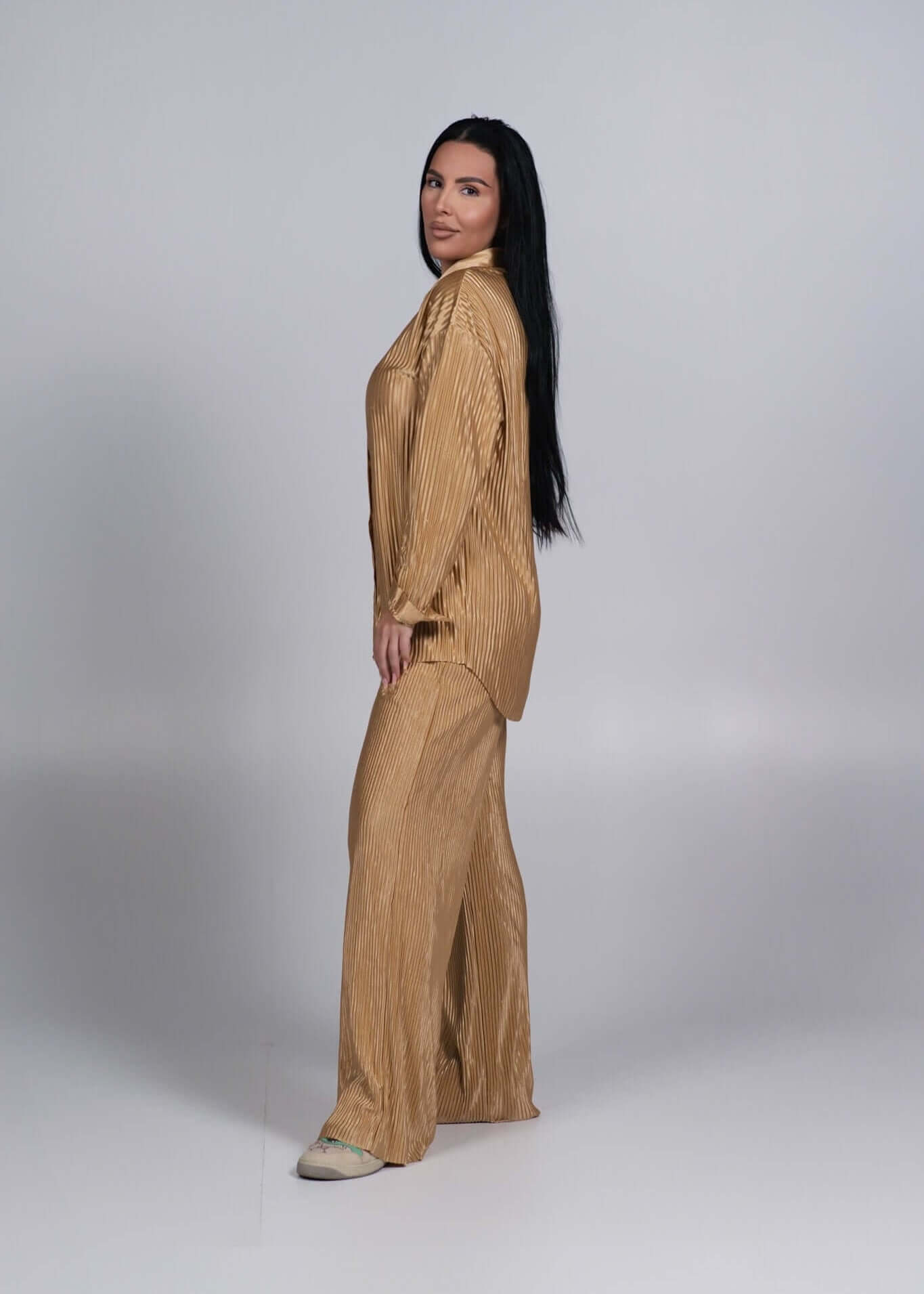 Compleu satinat plisat 2 piese ALLURE auriu, model femeie vazut din lateral pe fundal gri simplu Main image