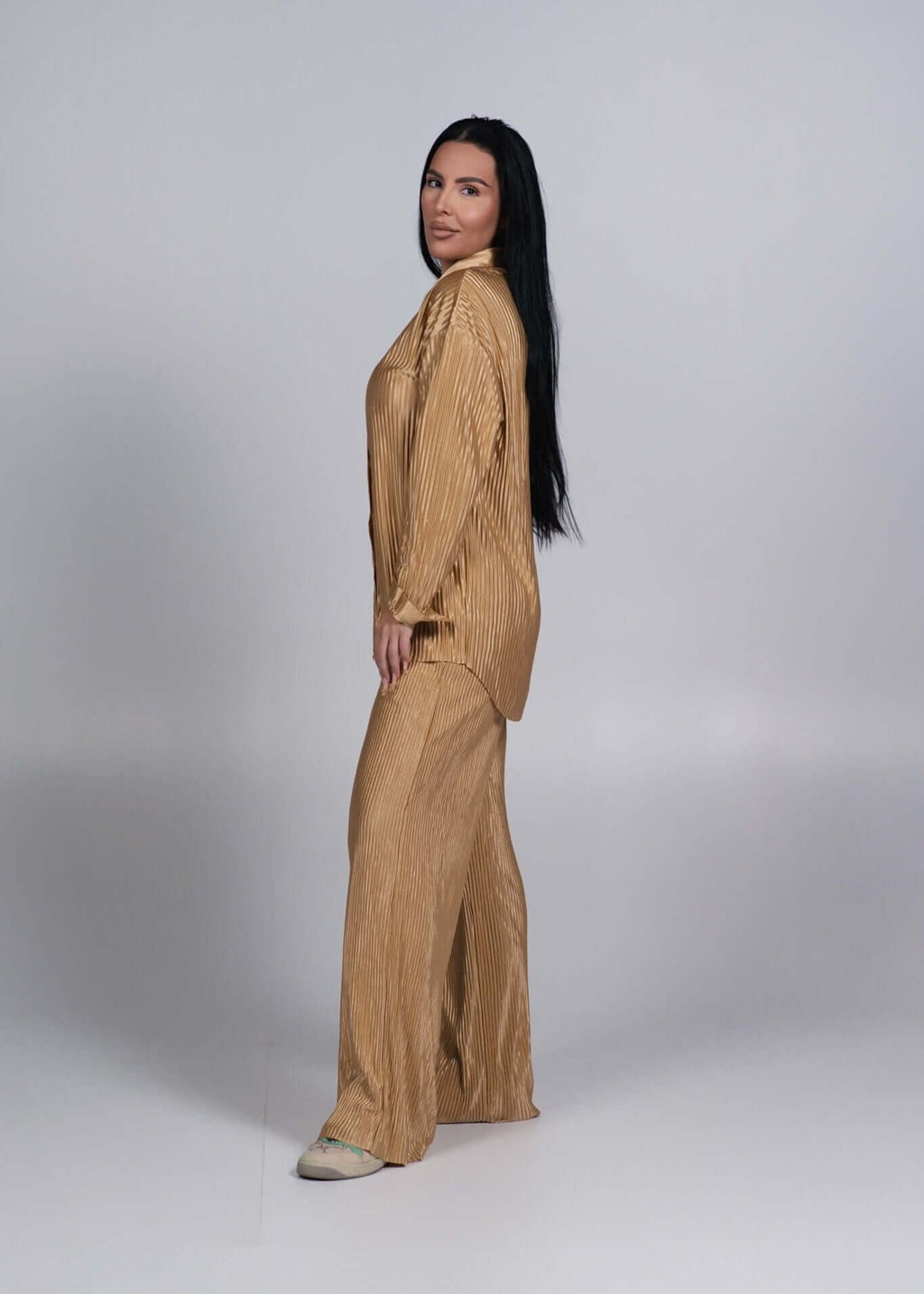 Compleu satinat plisat 2 piese ALLURE auriu, model femeie vazut din lateral pe fundal gri simplu