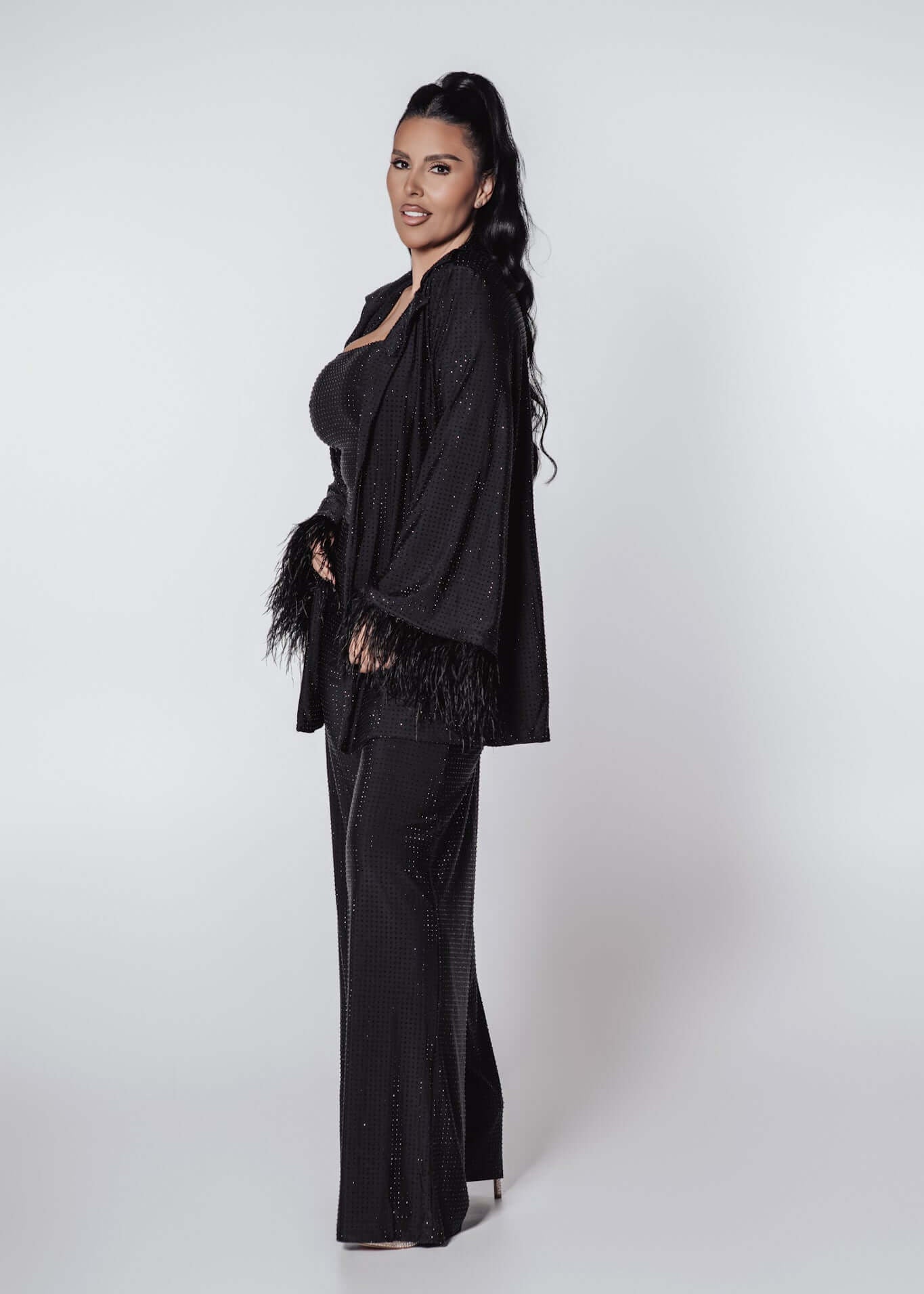 Compleu Bling Miray negru din lycra cu cristale, bustieră, pantaloni evazați și mantou elegant cu pene, model de seară