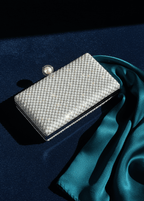 Clutch argintiu SIA Crystal Pearl cu cristale și închizătoare perlă, fotografiat pe catifea bleumarin cu eșarfă verde smarald
