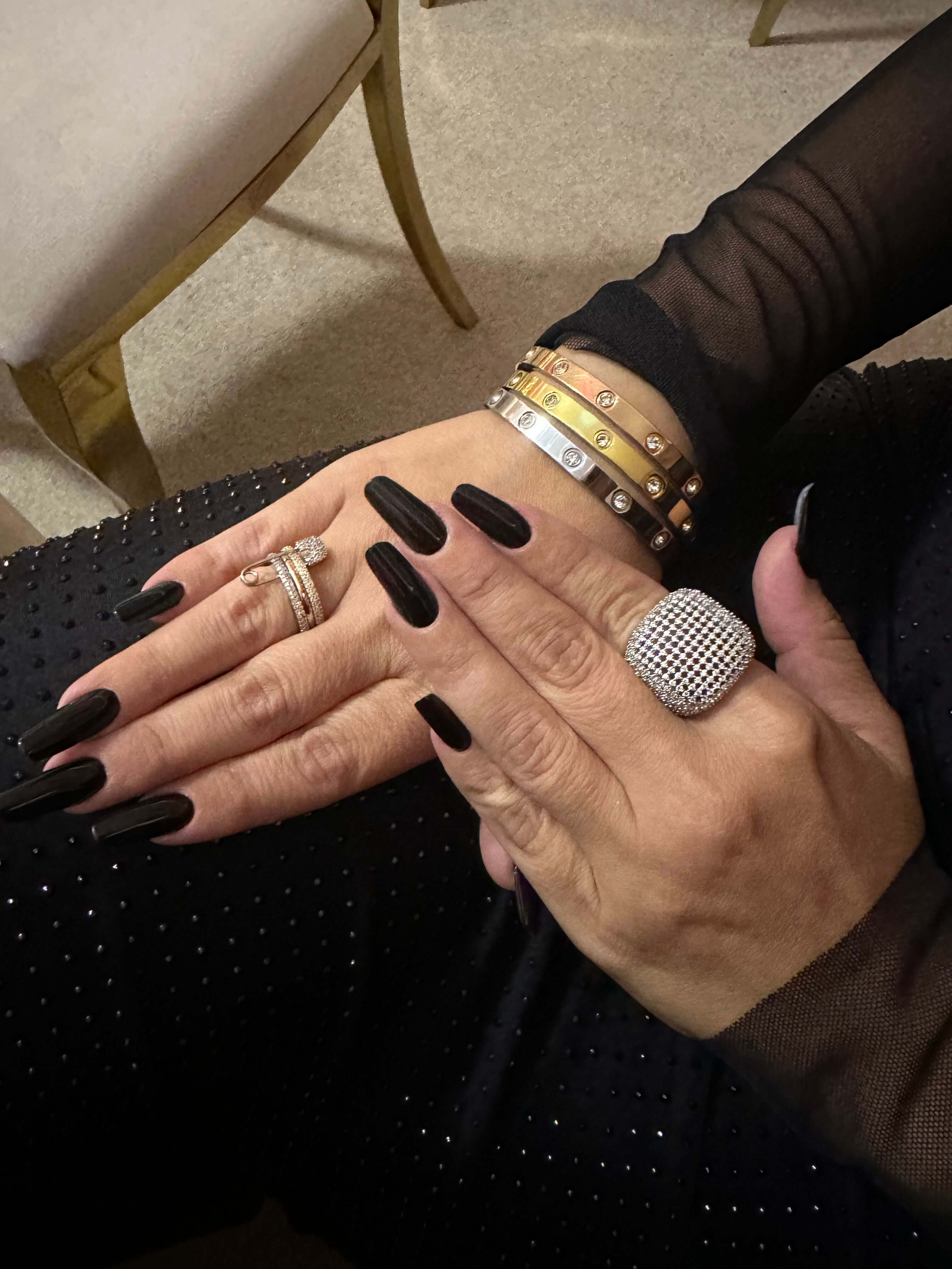 Femeie cu inel glamour argintiu și brățări elegante pe mâini, îmbrăcată în negru