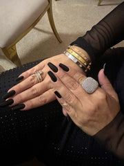Femeie cu inel glamour argintiu și brățări elegante pe mâini, îmbrăcată în negru