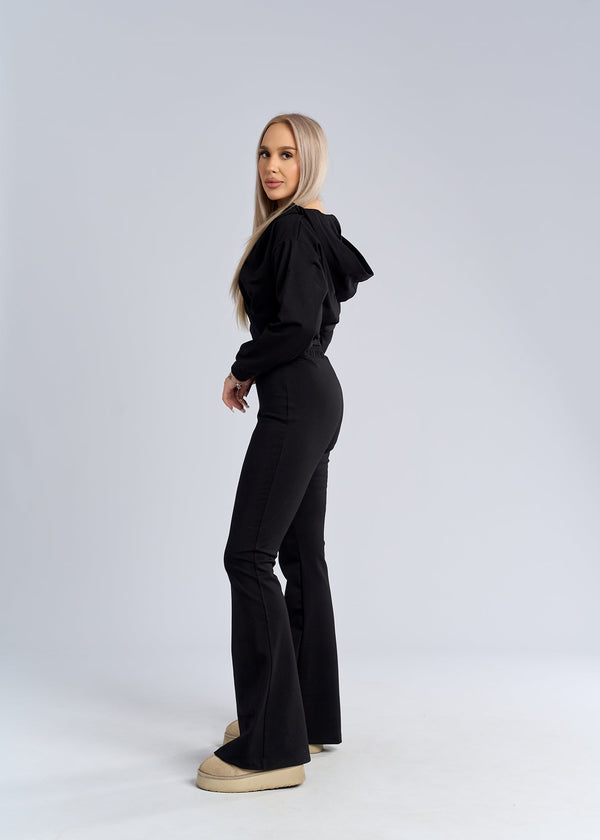Alt Tag: hanorac cropped negru cu fermoar și glugă, purtat cu pantaloni evazați, vedere laterală pe fundal studio alb