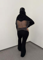 Model purtând SIA Pantaloni tip trening evazați "FLARE" cu partea din spate vizibilă, pantaloni negri confortabili și moderni.