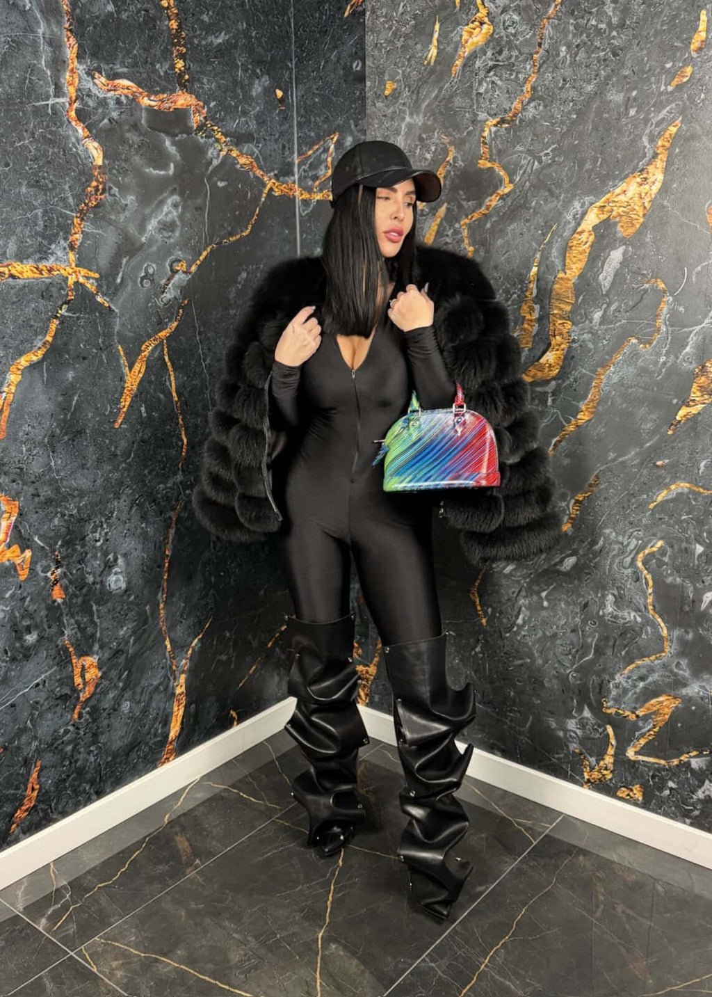 Femeie purtând SIA Venom jumpsuit, salopeta modelatoare neagră, cu fermoar, accesorii elegante, pantaloni lungi și geantă colorată.