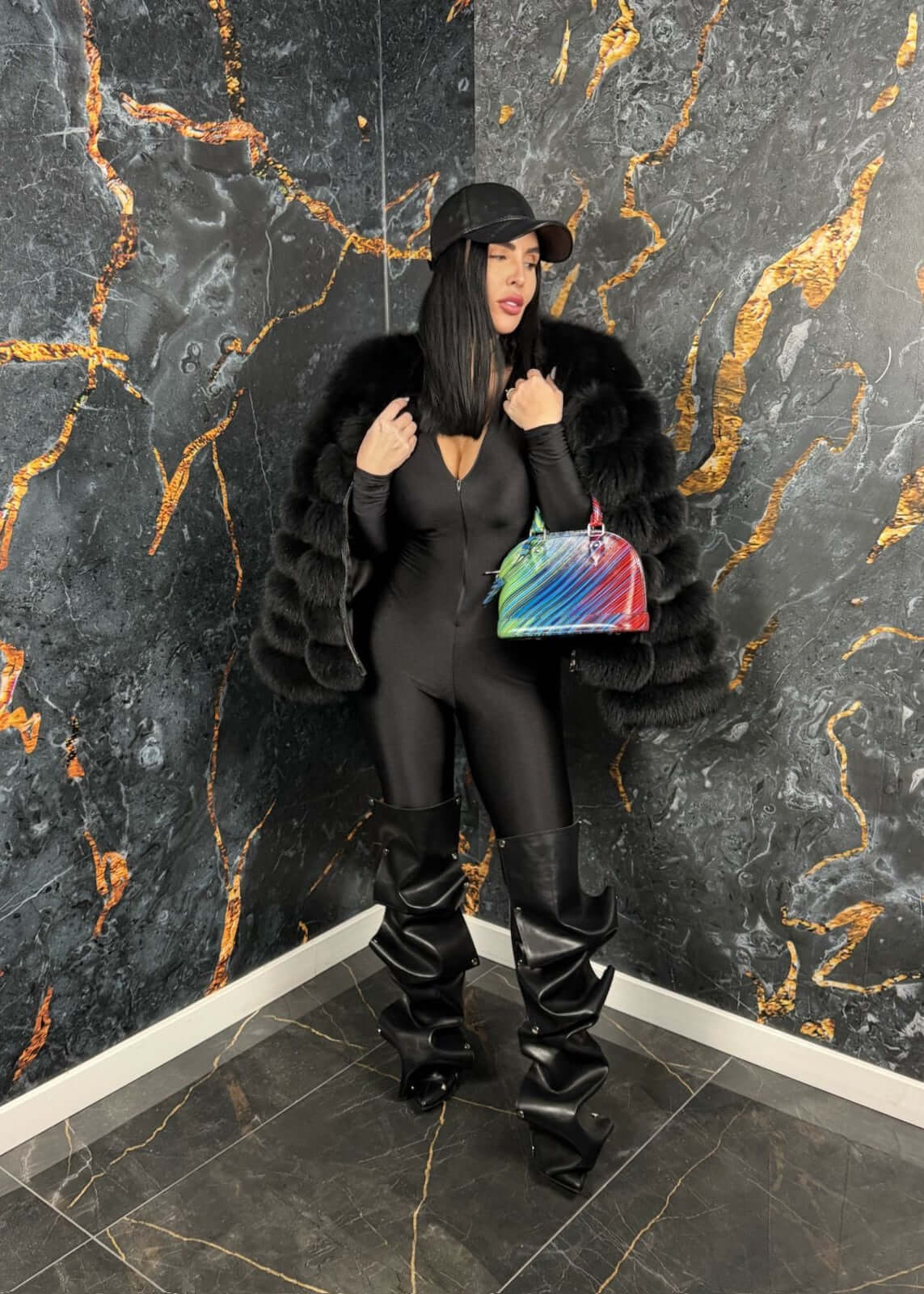 Femeie purtând SIA Venom jumpsuit, salopeta modelatoare neagră, cu fermoar, accesorii elegante, pantaloni lungi și geantă colorată.