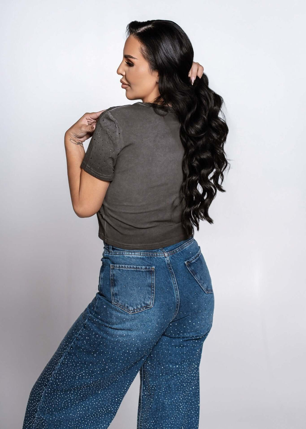 Blugi talie înaltă „CRYSTAL DENIM” cu cristale, croială lejeră ușor evazată, vedere spate pe model feminin