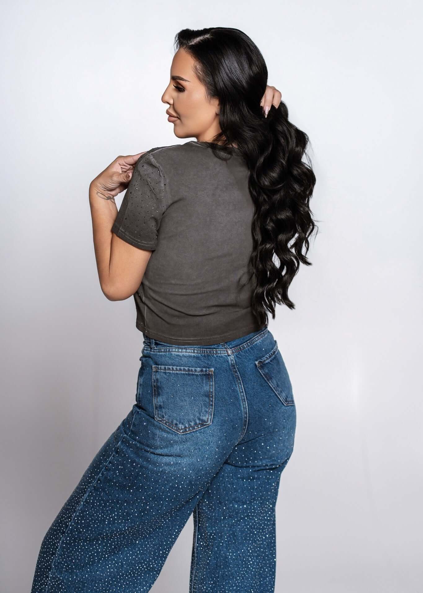 Blugi talie înaltă „CRYSTAL DENIM” cu cristale, croială lejeră ușor evazată, vedere spate pe model feminin