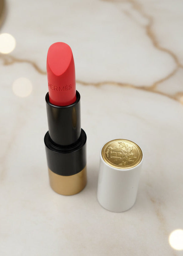 Ruj Rouge Hermès Satin Lipstick Rose Mexique 42 deschis pe masă de marmură, cu capac alb și auriu alături