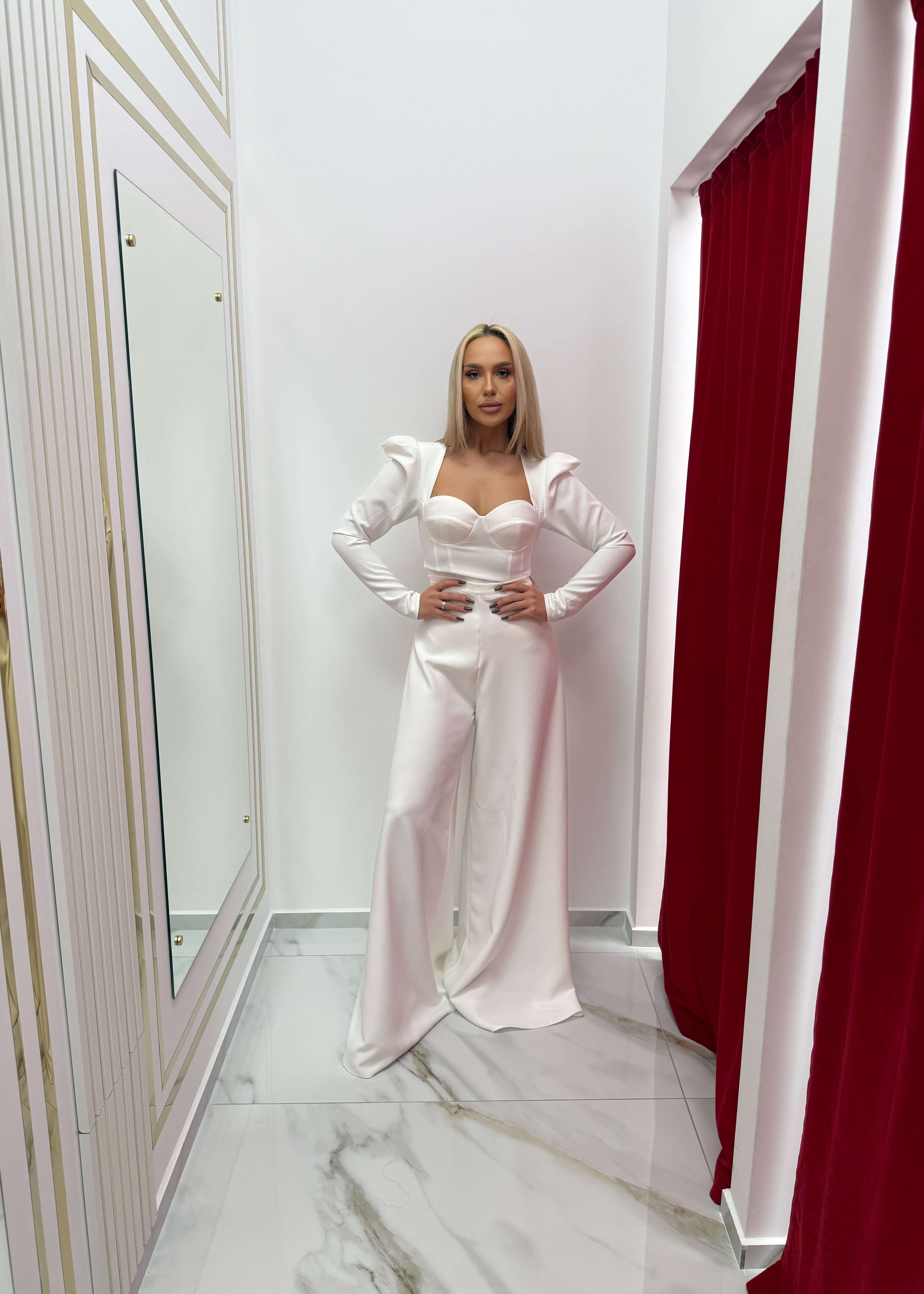 Femeie purtând Set Aura – Top Aura + Wide Pants, prezentând eleganță modernă și rafinament, într-o cabină de probă elegantă.