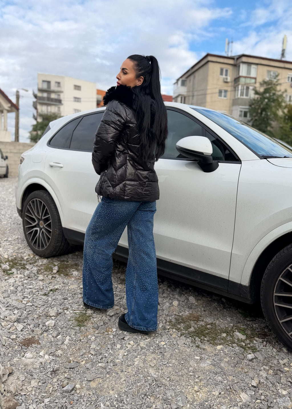 Blugi talie inalta CRYSTAL DENIM cu cristale, lejer evazati, purtati cu geaca neagra langa masina alba, tinuta casual glam