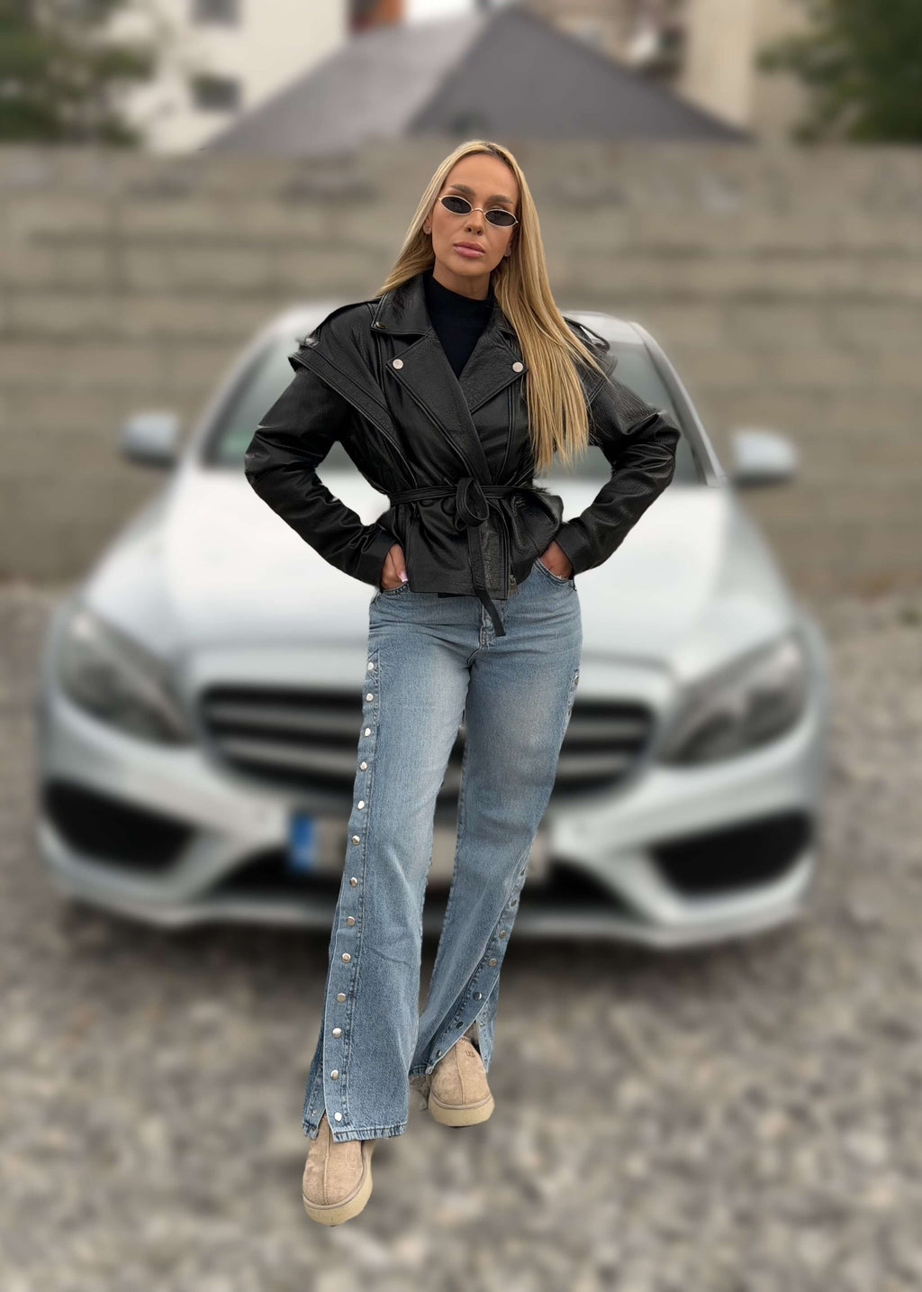 Blugi cu capse laterale SNAP ME, model urban cu jachetă neagră din piele în fața unei mașini argintii