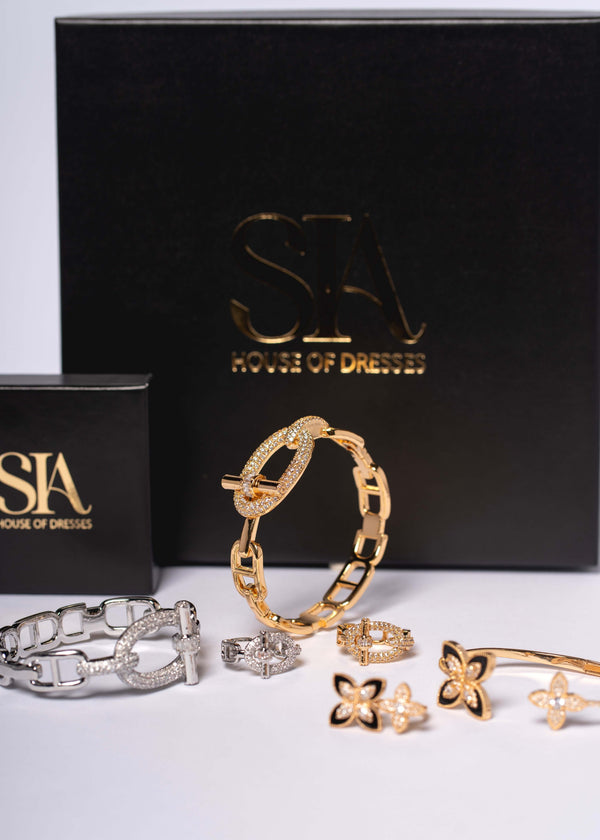 Set SIA Urban Icon cu brățară și inel cu cristale, bijuterii aurii și argintii expuse în fața cutiei SIA House of Dresses