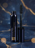 Estée Lauder Double Wear Zero-Smudge Lengthening Mascara, un tub elegant de mascara cu aplicator, pe un fundal artistic albastru.