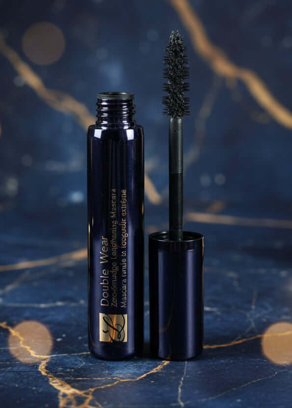 Estée Lauder Double Wear Zero-Smudge Lengthening Mascara, un tub elegant de mascara cu aplicator, pe un fundal artistic albastru.