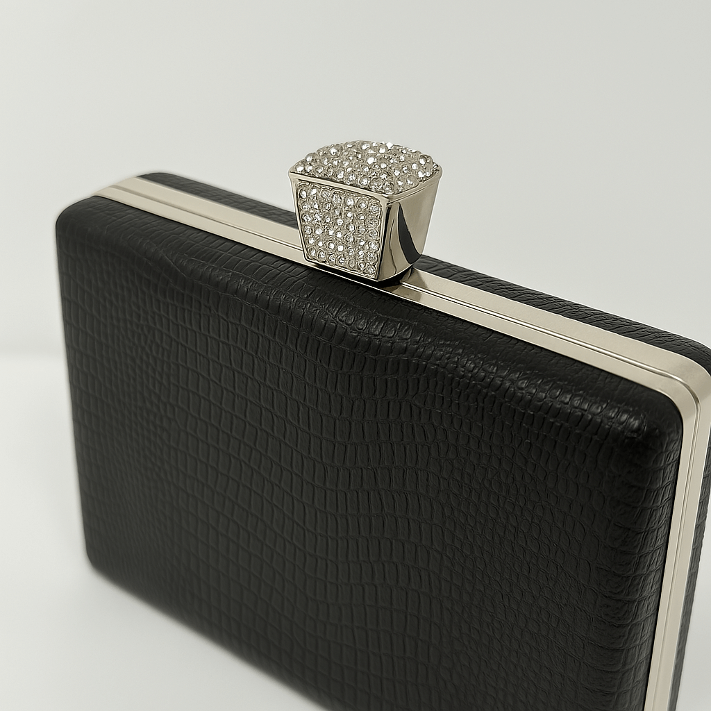 Geanta clutch neagră elegantă cu detalii argintii și textură rafinată pentru ținute glam și minimaliste, curea bijuterie strălucitoare.