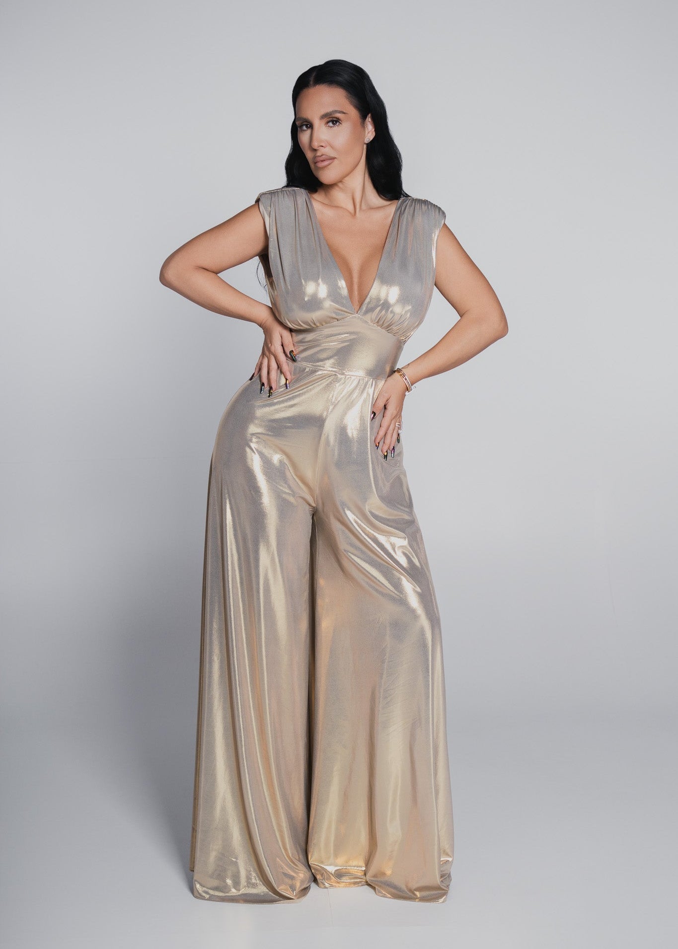 Salopeta Bling Illusion Estera din lycra metalizată aurie, cu decolteu adânc și croială largă, ideală pentru ținute de seară