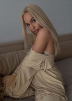 Compleu Bling Miray set 3 piese lycra cu cristale, bustieră, pantaloni evazați și mantou elegant pe model blond așezat pe canapea