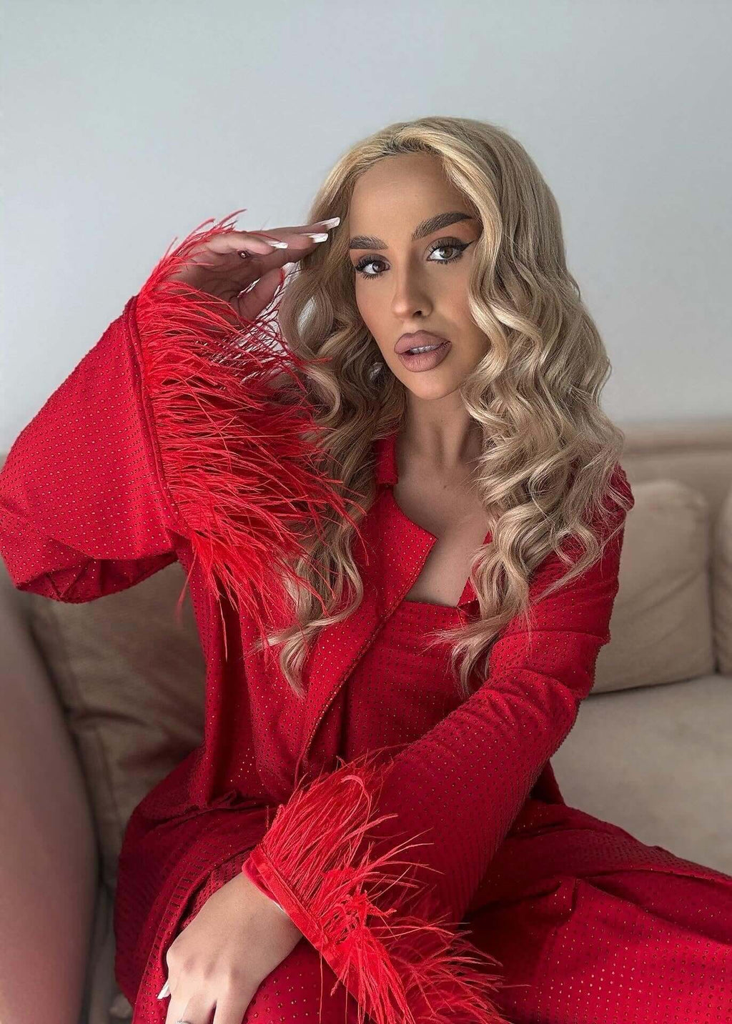 Compleu Bling Miray roșu elegant, set 3 piese cu pene și cristale, bustieră și pantaloni, model feminin pe canapea